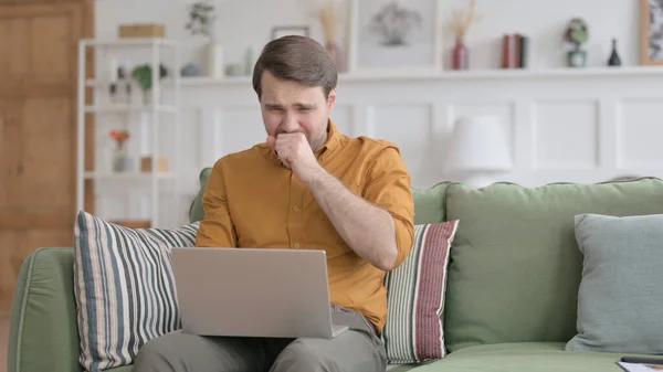 Hombre joven con la tos del ordenador portátil en el sofá —  Fotos de Stock