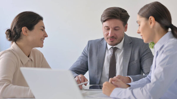 Весёлые молодые мужчины и женщины-бизнесмены разговаривают в офисе