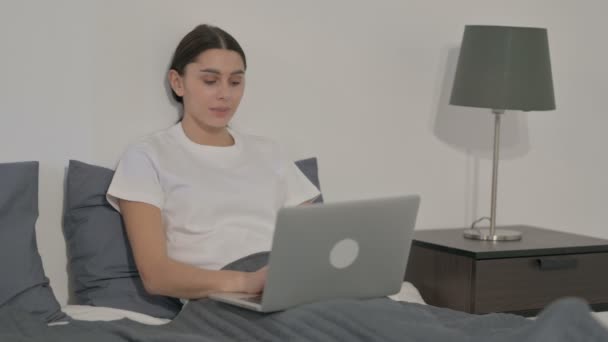 Іспанська жінка показує великі пальці вгору знак під час використання ноутбука в ліжку — стокове відео