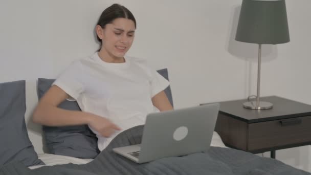 Mujer hispana con dolor de espalda mientras usa el ordenador portátil en la cama — Vídeos de Stock