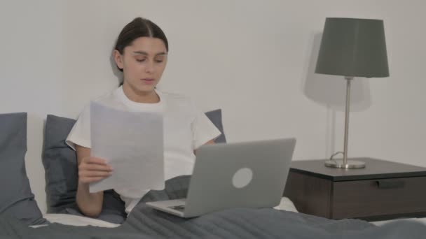 Испанская женщина с документами для чтения ноутбука в постели — стоковое видео