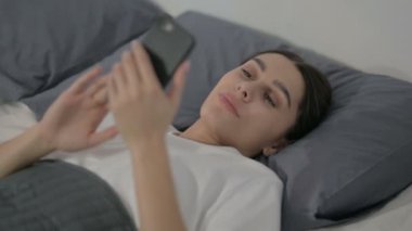 Yatakta yatarken Smartphone kullanan İspanyol Kadın 'a yaklaş.