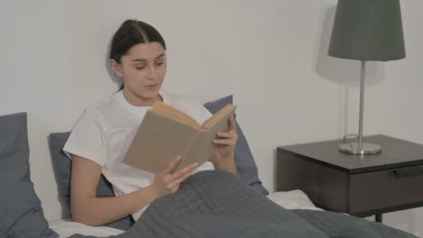 西班牙女人坐在床上看书 — 图库视频影像