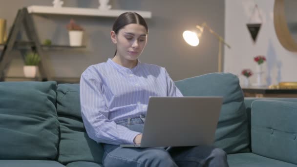 Hiszpanka z laptopem z bólem szyi na kanapie — Wideo stockowe