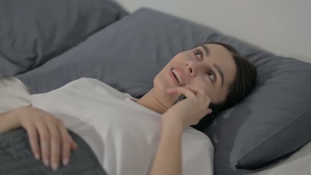 Nahaufnahme einer hispanischen Frau, die im Bett telefoniert — Stockvideo