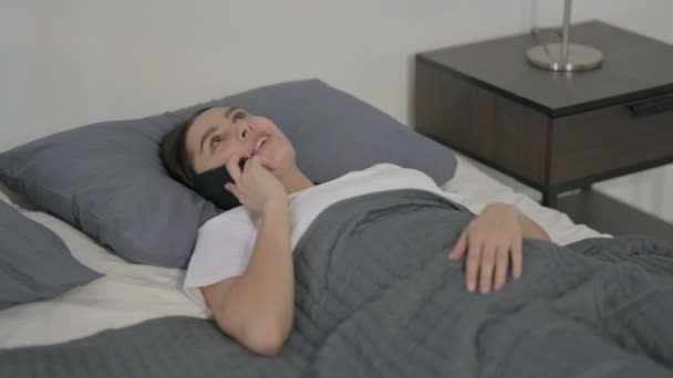 ベッドで寝ている間に電話で話すヒスパニック系女性 — ストック動画