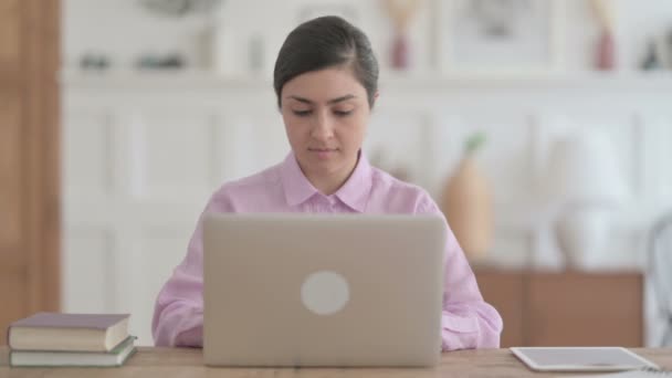 Mulher indiana olhando para a câmera ao usar o laptop no escritório — Vídeo de Stock