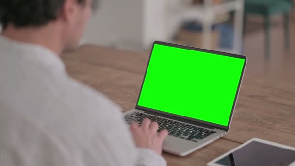 Молодий чоловік користується ноутбуком з зеленим екраном — стокове відео