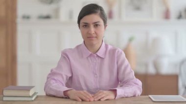 Ofiste otururken kameraya gülümseyen Hintli kadın
