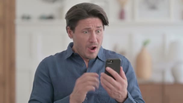 A fiatalember arcképe reagál a veszteségre okostelefonon — Stock videók