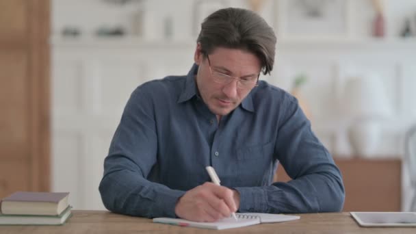 Jonge man die op papier schrijft op kantoor — Stockvideo