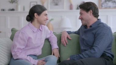 Genç adam koltukta otururken Hintli kadınla konuşuyor. 