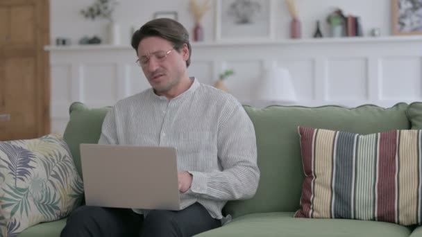 Jongeman met laptop met nekpijn op de bank — Stockvideo