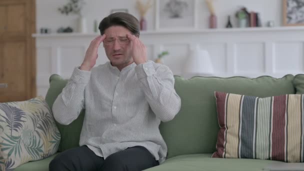 Unge man som har huvudvärk när han sitter på soffan — Stockvideo