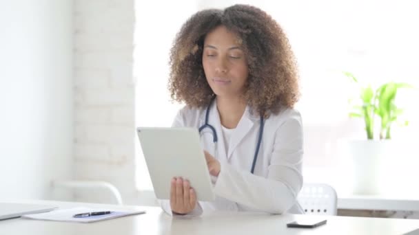 Afrcian Lekarz stosujący tabletkę podczas siedzenia w klinice — Wideo stockowe