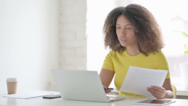 Afrikaanse vrouw met laptop lezende documenten in Office — Stockvideo