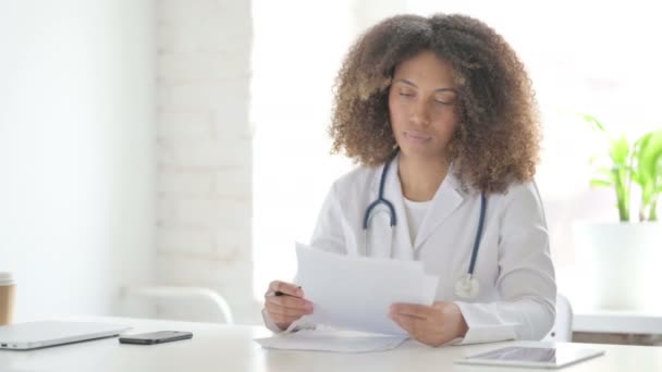 Afrcian Arzt liest Dokumente, während er in der Klinik sitzt — Stockvideo
