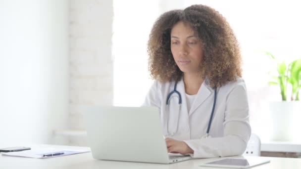 Afrcian Doctor glimlachen op de camera tijdens het gebruik van laptop in de kliniek — Stockvideo