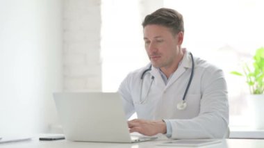 Ofiste dizüstü bilgisayar kullanırken Erkek Doktor İşaretini Gösteriyor 