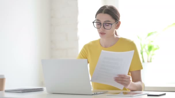 Жінка читає документи під час використання ноутбука в офісі — стокове відео