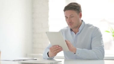 Ofiste otururken Tablet kullanan adam