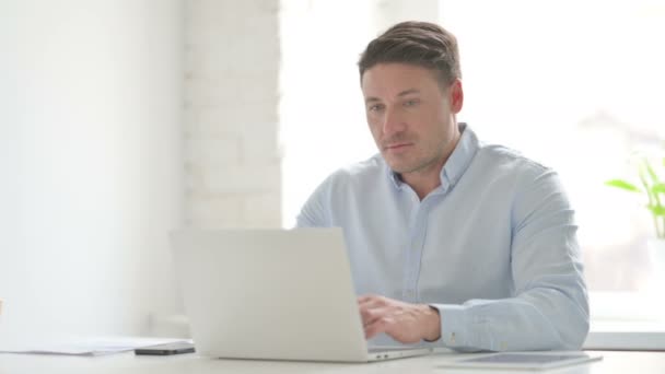 Hombre celebrando el éxito mientras usa el ordenador portátil en la oficina — Vídeo de stock