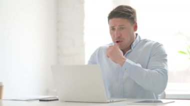 Ofiste dizüstü bilgisayar kullanırken öksüren adam 