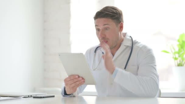 Doctor masculino haciendo videollamada en la tableta en la oficina — Vídeo de stock