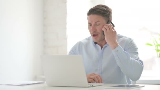 Dühös ember beszél telefonon használata közben Laptop — Stock videók