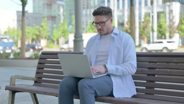 Beschäftigter Mann Mittleren Alters Sitzt Mit Laptop Draußen Auf Bank — Stockvideo