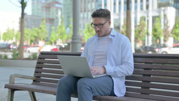 Mann Mittleren Alters Mit Laptop Blickt Auf Kamera Während Draußen — Stockvideo