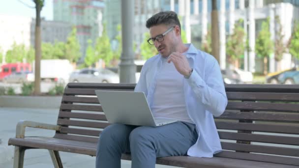 坐在户外长椅上的中年男子使用笔记本电脑时颈部疼痛 — 图库视频影像
