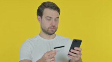 Online Shopping on Smartphone by Casual Young Man on Yellow Background 