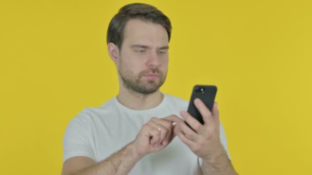 Casual Young Man Browsing Smartphone Yellow Background — Vídeo de stock