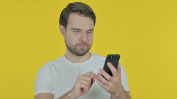 Hombre Joven Casual Celebrando Smartphone Sobre Fondo Amarillo — Vídeos de Stock