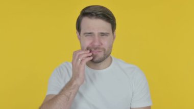 Sarı arka planda dişleri ağrıyan sıradan bir genç adam.