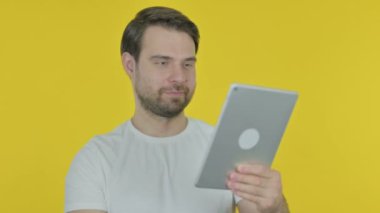 Video Call on Tablet by Casual Young Man on Yellow Background 
