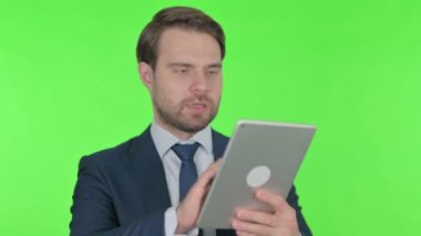 Young Adult Businessman using Digital Tablet on Green Background 