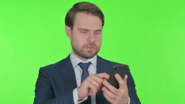 Young Adult Businessman Browsing Smartphone Green Background — Stockvideo