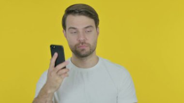 Casual genç adam konuşan üzerinde telefon sarı arka plan 