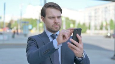 Middle Aged Businessman Browsing Internet on Smartphone Outdoor