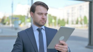 Upset Middle Aged Businessman Reacting to Loss on Tablet Outdoor