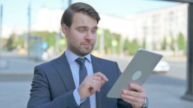 Middle Aged Businessman Celebrating Online Win on Tablet Outdoor