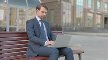 Rejecting Young Businessman in Denial While using Laptop Sitting Outdoor on Bench 