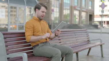 Upset Casual Young Man Reacting to Loss on Tablet Outdoor