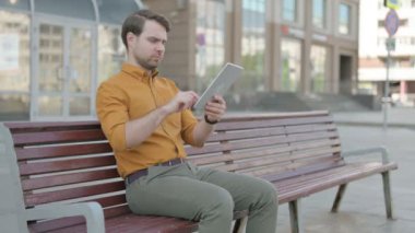Casual Young Man Celebrating Online Win on Tablet Outdoor