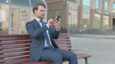 Young Businessman Celebrating Online Success on Smartphone Outdoor