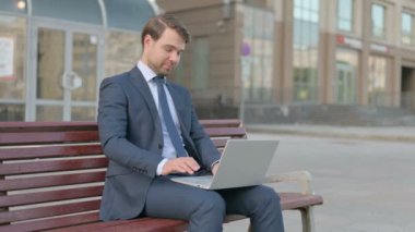 Young Businessman with Laptop Showing Thumbs Up Sign While Sitting Outdoor on Bench 