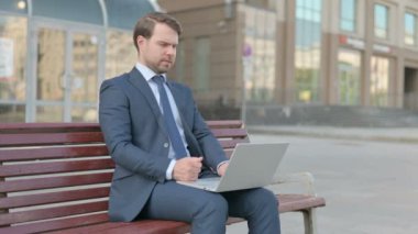 Thinking Middle Aged Businessman Using Laptop while Sitting Outdoor on Bench