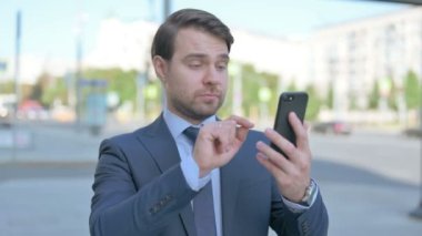 Upset Middle Aged Businessman Reacting to Loss on Smartphone Outdoor